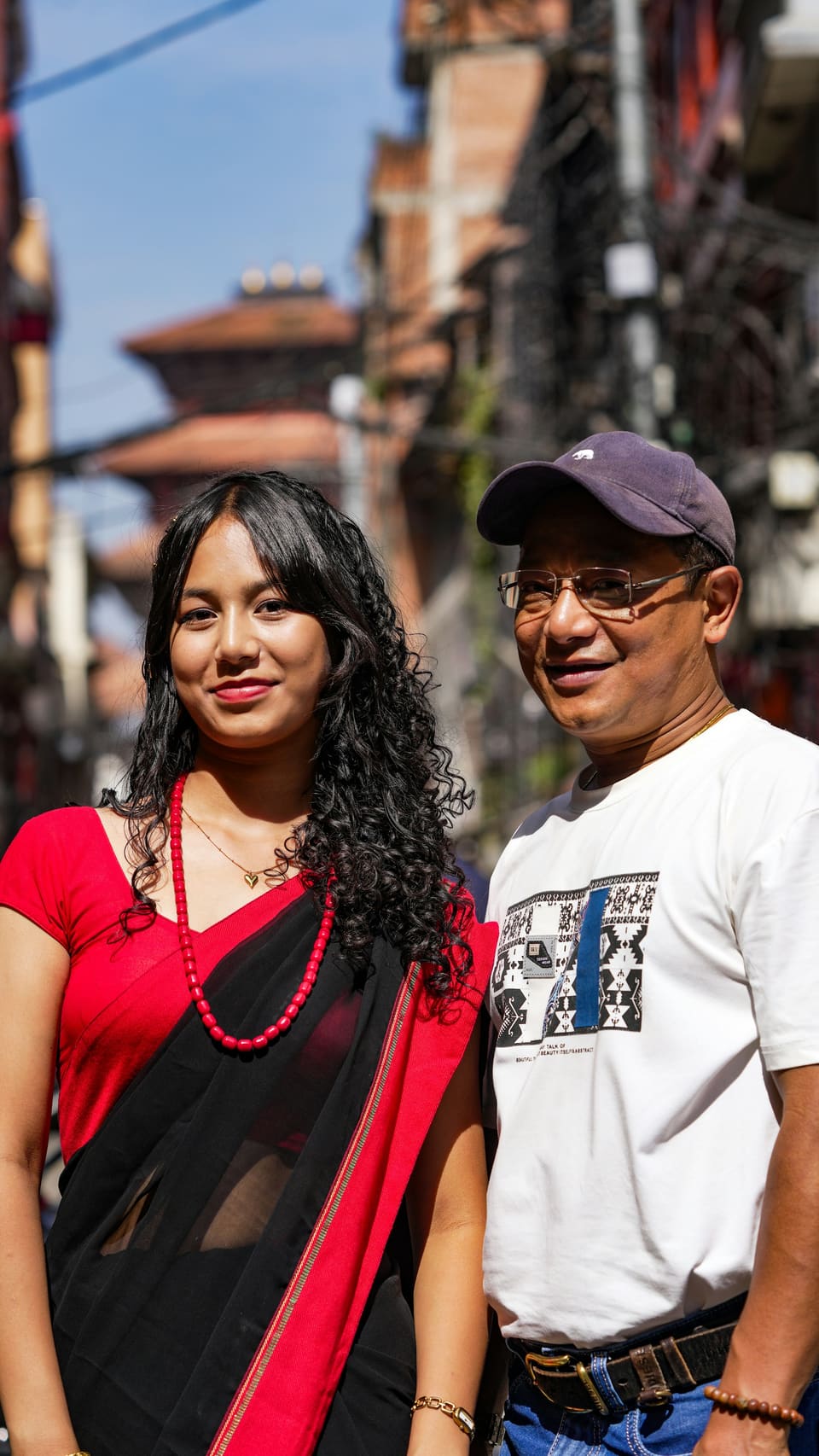 A young woman in a red sari standing beside her father