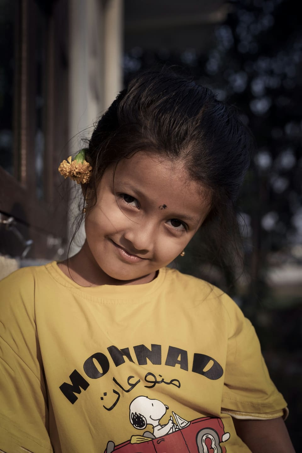 A girl with a flower in her hair smiling at the camera