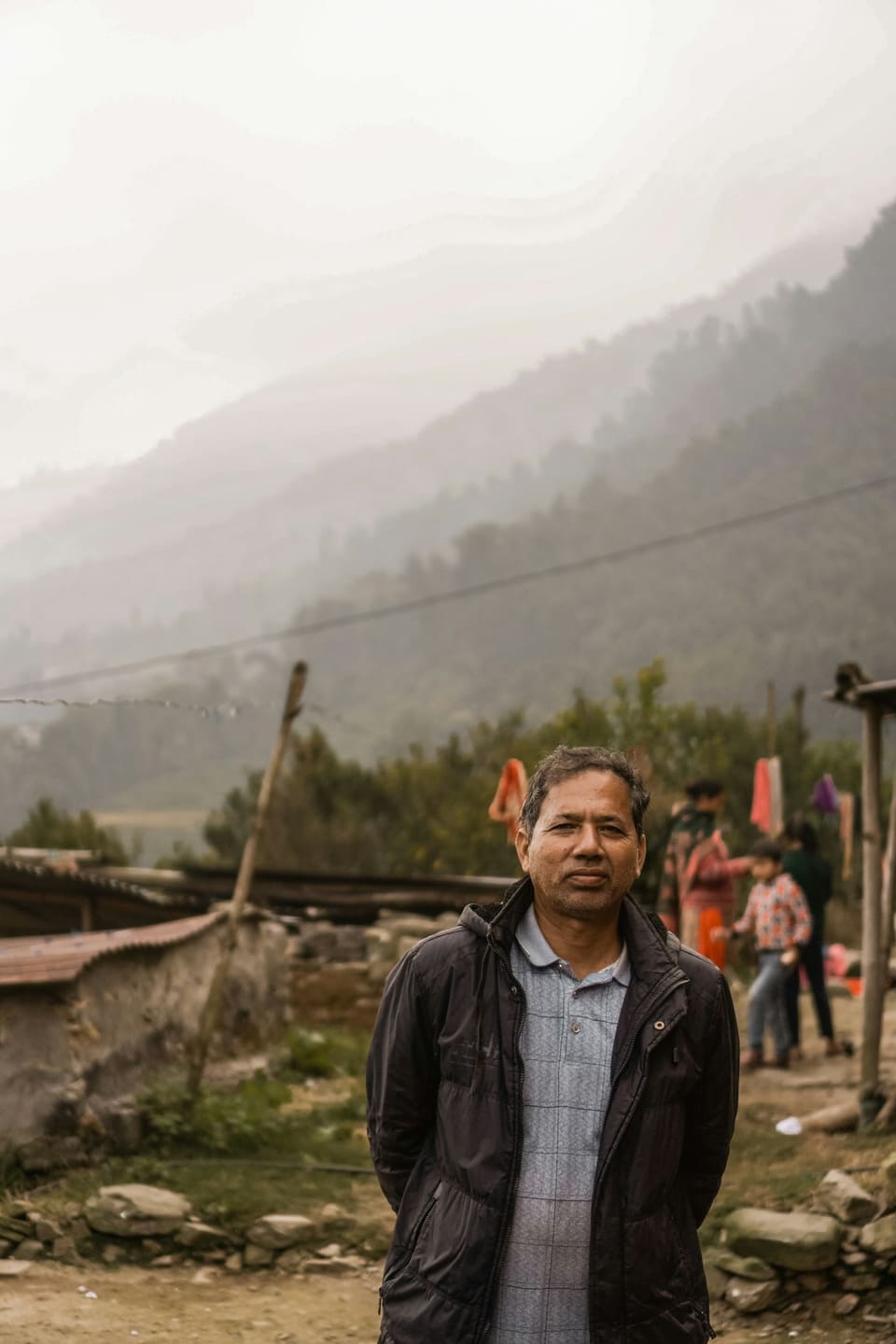 A man standing in a hillside village on a misty morning