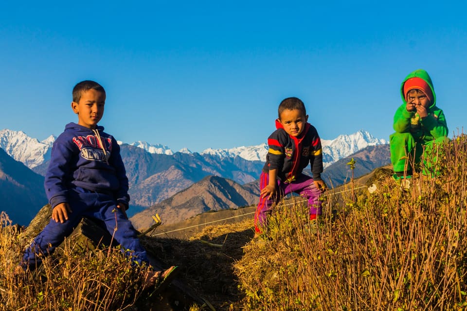 Children resting on hay on a hilltop with snow mountains behind